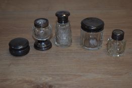 A collection of cut glass scent and dressing table jars, with silver and white metal mounts/lids,