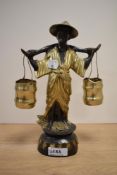 A gilded metal study of a traditionally dressed Chinese figure, carrying two pails.