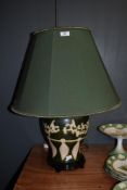 A glazed pottery table lamp, of Oriental design, on green ground, with shade, measuring 64cm tall