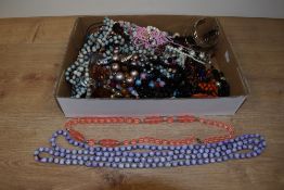 An assorted collection of costume jewellery, including a string of pink plastic beads, a white metal