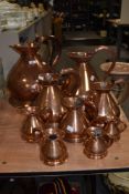 A group of nine graduating copper measures, ranging from 2 gallons to 1/2 gill
