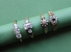 A 9ct gold three stone ring set with Cubic Zirconiums, together with three other 9ct gold rings,