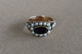 A late George III mourning ring set with a central oval faceted amethyst surrounded by half section