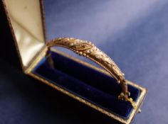 A 9ct gold hinged bangle set with rows of seed pearls and beaded decoration, approximately 8 grams,