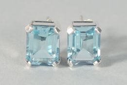 A PAIR OF SILVER EMERALD CUT TOPAZ EAR STUDS.