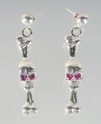 A PAIR OF SILVER SKULL AND BONE DROP EARRINGS.