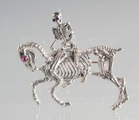 A SILVER ANATOMICAL HORSE AND SKELETON RIDER BROOCH.