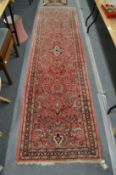 A Persian style runner, pink ground with floral decoration 310cm x 80cm.