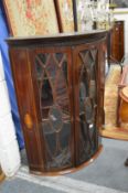 An inlaid mahogany bowfront two door hanging corner display cabinet.