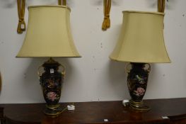 A pair of urn shaped pottery table lamps with shades, the lamps painted with birds and flowers.