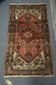 A small Persian woollen rug with stylised decoration 117cm x 67cm.