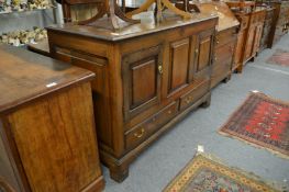 An oak coffer style cabinet with two panel doors and two drawers on bracket feet.