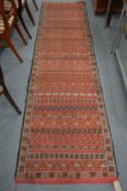 A Eastern runner, red ground with bands of geometric decoration 324cm x 84cm.
