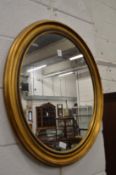 A gilt framed oval wall mirror.