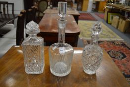 Three cut glass decanters and stoppers.