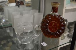 A bottle of Remy Martin XO excellance cognac with a small Remy Martin jug and six frosted glass