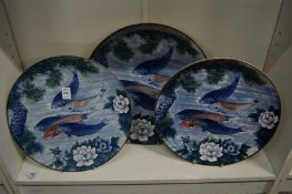 A set of three large plates depicting carp.