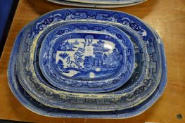Four blue and white willow pattern plates.