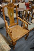 A walnut high back open armchair with canework seat.