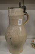 A large stoneware jug with pewter lid.