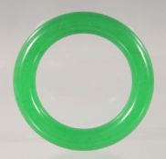 A CHINESE GREEN JADE BANGLE 8.5cm diameter.