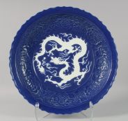 A LARGE CHINESE SACRIFICIAL BLUE DRAGON CHARGER, the centre with carved dragon in white;