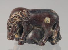 A CARVED WOOD NETSUKE modelled as horses. 4.5cm long.