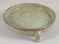 A CHINESE CRACKLE GLAZE CELADON SHALLOW CENSOR/ BRUSHWASHER, on three feet. 14cm diameter.