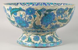 A LARGE TURKISH GLAZED POTTERY FOOTED BOWL, painted with floral motifs, 39.5cm diameter.