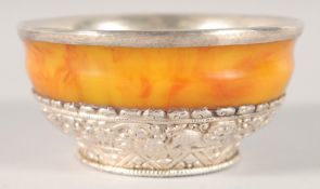 A TIBETAN SILVER MOUNTED AMBER BOWL, the interior with silver lining, 11cm diameter.