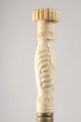 A WALKING STICK WITH CARVED BONE HANDLE as clasped hands.