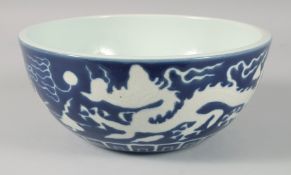 A LARGE CHINESE SACRIFICIAL BLUE DRAGON BOWL, the exterior with carved white dragons and clouds, the