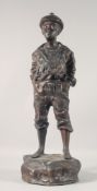 A CAST BRONZE FIGURE OF A BOY WHISTLING, his hands in his pockets, stood on a rock. 29ins high.