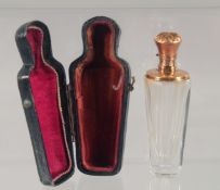A CUT GLASS SCENT BOTTLE WITH HINGED GOLD TOP, cased. 9cm high