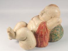 A CARVED WOOD AND PAINTED CHINESE SLEEPING BOY. 20ins long.