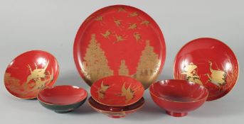 A COLLECTION OF SEVEN JAPANESE RED LACQUER DISHES, four pieces with gilt decoration depicting