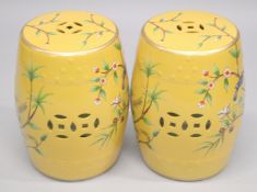 A PAIR OF CHINESE STYLE PORCELAIN BARREL SEATS, yellow ground painted with birds. 18ins high.