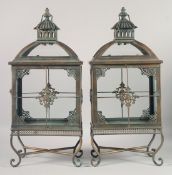 A PAIR OF ORNATE METAL LANTERNS on curving feet. 22ins high.
