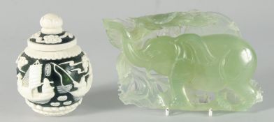 A SMALL CHINESE GREEN GLASS JAR with raised decoration of boating scenes and figures, bearing two