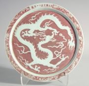 A CHINESE UNDERGLAZED RED DRAGON CIRCULAR DISH. 11ins high.