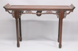 A CHINESE HARDWOOD ALTER TABLE with curving ends and pierced and carved frieze. 5ft long x 1ft