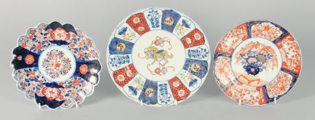 THREE JAPANESE IMARI PORCELAIN PLATES, one painted with a central dog, the other two with flora,