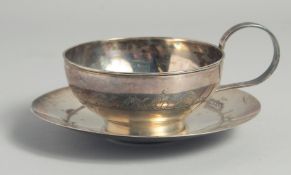 A LARGE IRAQI SILVER CUP AND SAUCER, with engraved decoration of camels and boats, weight 220g, (2