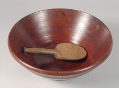 A TREEN CIRCULAR BUTTER BOWL and spoon. 12ins diameter