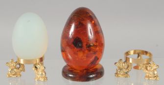 A PAIR OF OPAL AND AMBER EGGS on a stand.