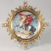 A PORCELAIN DISH DECORATED WITH NAPOLEON ON HORSEBACK, in an ornate brass frame. 18.5ins diameter.