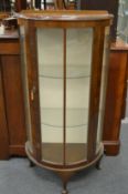 A walnut bow fronted display cabinet.