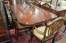 A mahogany twin pillar dining table and six chairs, two with arms.