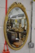 A gilt framed oval mirror.
