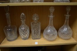 A pair of cut glass decanters and three others.